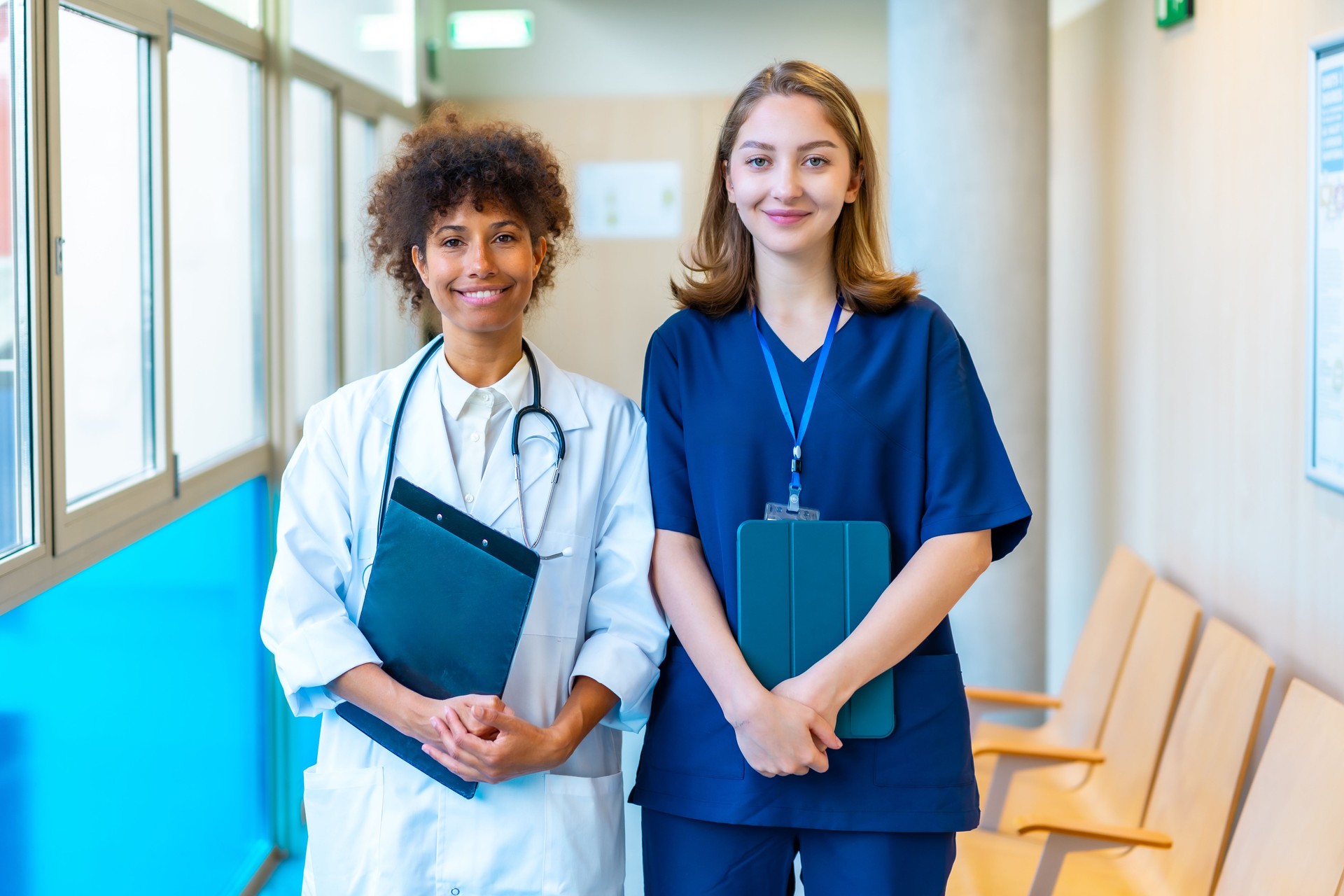 Doctor and nurse smiling together in hospital corridor